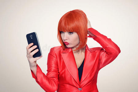 迷人的红头发女人在智能手机上自拍