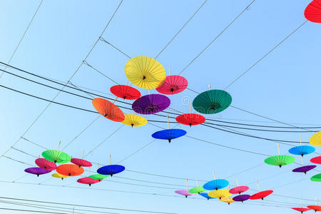 彩色雨伞挂在电线和天空背景上