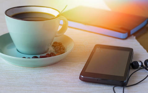 一杯带电话和笔记本的咖啡。 早上冷静的概念
