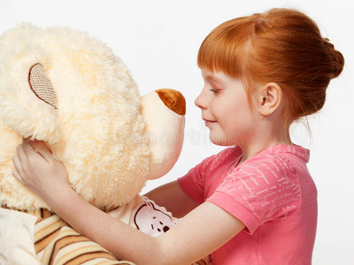 特写一位带着熊玩具的微笑红头发女孩的肖像