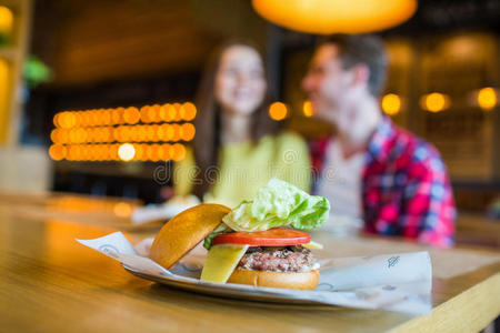 一对男女-吃汉堡包和在快餐店喝酒;专注于这顿饭照片