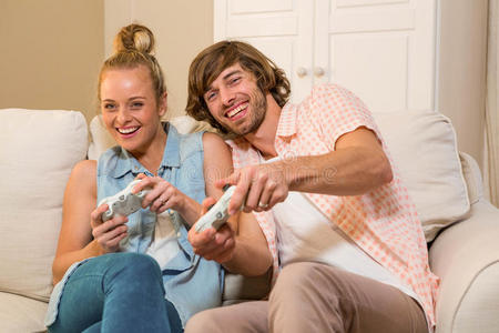 一对可爱的夫妇坐在沙发上玩电子游戏