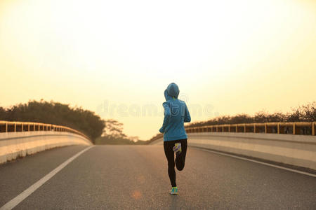 健身女子跑步运动员在日出路上跑步