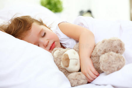 小女孩和泰迪熊睡在床上