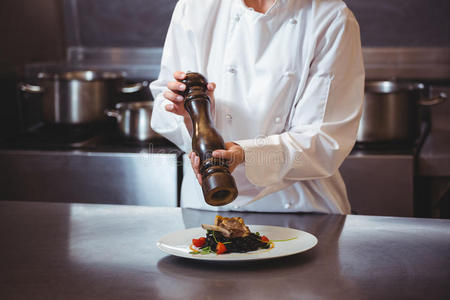 厨师在菜上撒胡椒粉照片