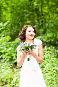 新娘拿着一束白色的马蹄莲和蓝色的花