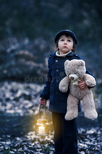 可爱的孩子，拿着灯笼和泰迪熊在森林里