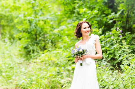 新娘拿着一束白色的马蹄莲和蓝色的花