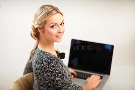 一幅女商人坐在办公桌前拿着笔记本电脑的肖像