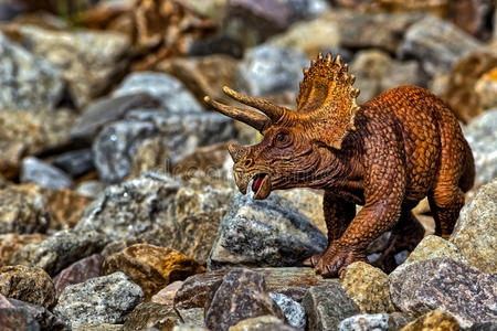 棕色三足恐龙在岩石中行走照片