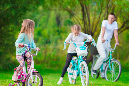 一个年轻的父亲和孩子们在夏天温暖的日子骑自行车