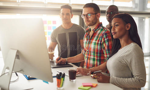 四名年轻工人站在电脑周围