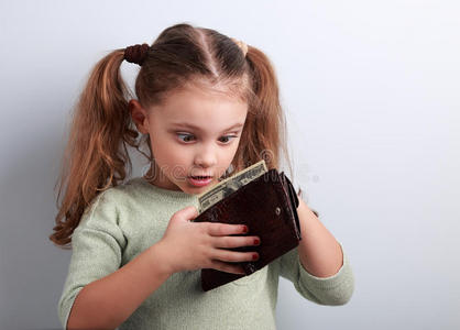 可爱的令人惊讶的小女孩拿着娃娃看钱包