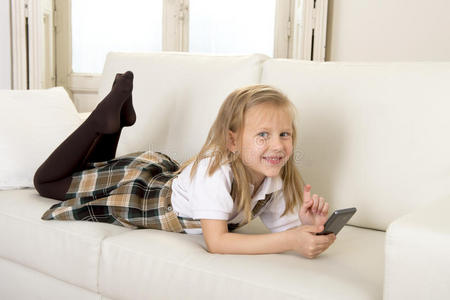女孩子金发躺在家里的沙发上，使用手机上的互联网应用程序