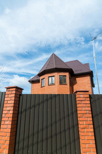 我在梯形屋顶特写的窗口有红屋顶和红砖的房子.红砖栅栏.