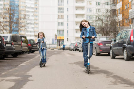 女孩骑着踢踏板车。