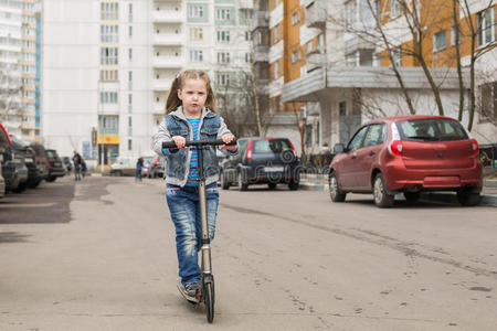 女孩骑着踢踏板车。