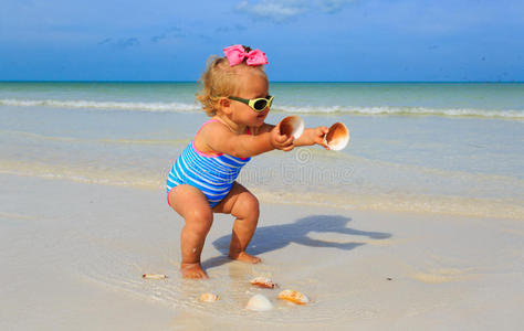 可爱的小女孩在海滩上玩贝壳