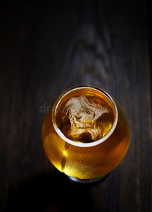 冷泡沫啤酒在一杯原始颜色的木背景上
