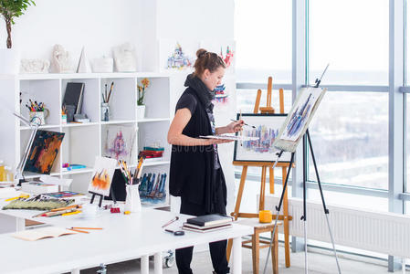 女画家画在艺术工作室使用画架。 一位年轻女子用水彩画在白色上的肖像