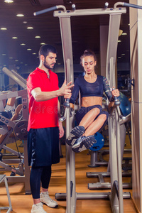 健身，运动，训练和人的概念私人教练帮助妇女与腹部肌肉按压