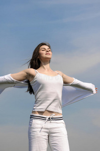 女孩在蓝天背景上呼吸新鲜空气.照片