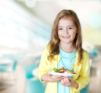 小女孩微笑着在咖啡馆背景下携带盘子沙拉。