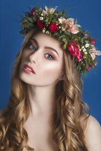 美丽的年轻女孩，她的头发上有一个蓝色花卉装饰。 戴花圈的女人。漂亮的脸。 时尚