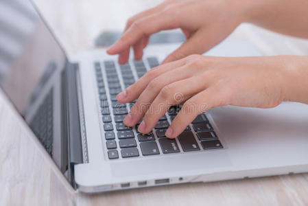 特写商务女性在笔记本电脑键盘上打字。