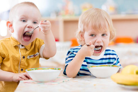 有趣的小孩子在幼儿园从盘子里吃东西