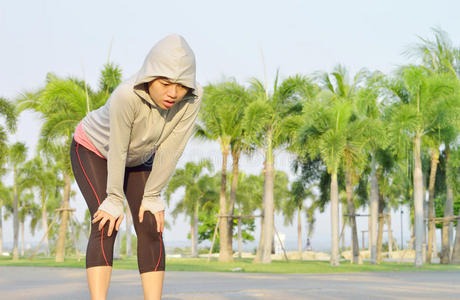 疲惫的女跑步者在努力奔跑后休息照片