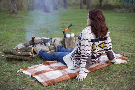 一个女孩坐在火炉边喝咖啡。