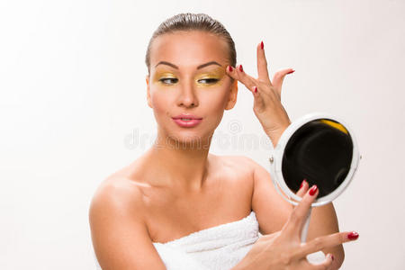黄金化妆。 棕色光滑的头发美丽的女人看着镜子