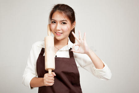 穿着围裙的亚洲面包师女士用木制擀面杖展示