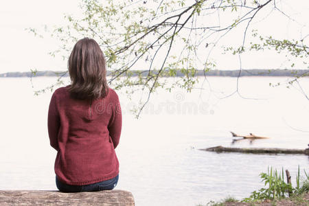 女人坐在湖边的树上