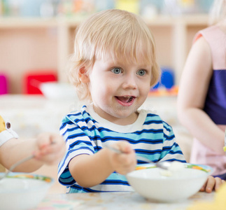 有趣的微笑孩子在幼儿园吃盘子