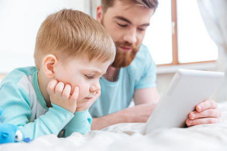 父亲和儿子在家在平板电脑上玩电脑游戏