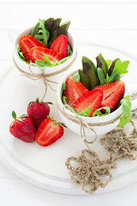 新鲜沙拉配草莓，阿鲁古拉，鳄梨和黑芝麻在白色杯子里