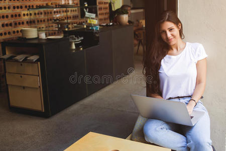 华丽的女性自由职业者使用上网本进行远程工作，而坐在现代咖啡店