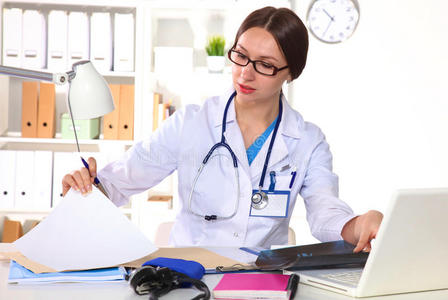 美丽的全科医生正在快乐地工作. 她手里拿着一堆文件照片