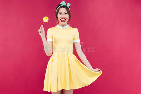 开朗可爱的小女孩站着拿着黄色的棒棒糖