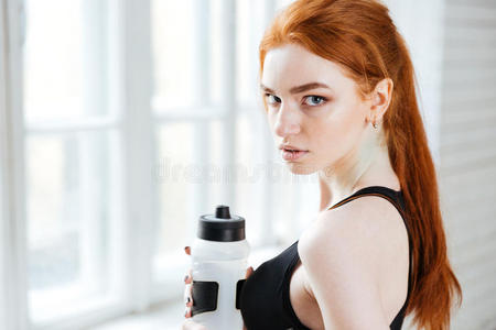 一个漂亮的健身女孩拿着瓶子的特写肖像