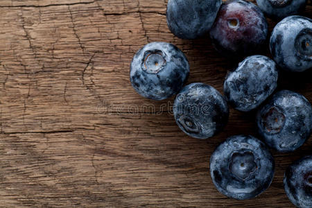 刚采摘的木制背景蓝莓。 多汁新鲜的蓝莓和绿叶在乡村的桌子上。