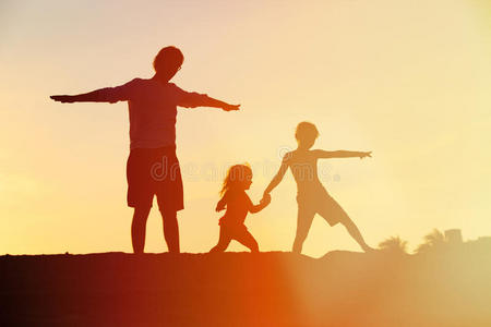父亲和儿子和女儿的剪影在日落时播放
