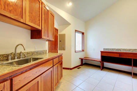 明亮的厨房室内有棕色储藏室，花岗岩台面和瓷砖地板。