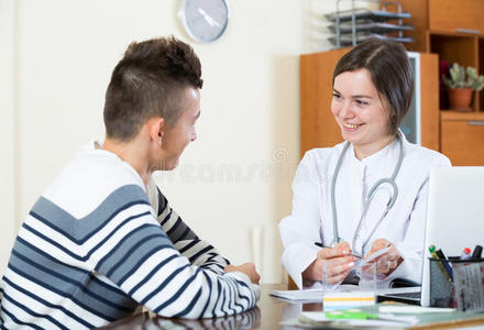 普通门诊女医生在办公室询问青少年病人照片