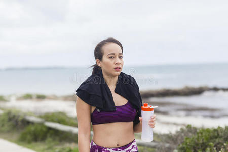 美丽的健身运动员妇女在锻炼后休息饮用水