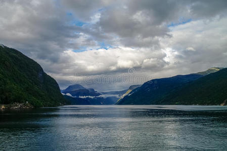 峡湾上空多云的天空。 有绿色森林的山脉，伊德福德，挪威