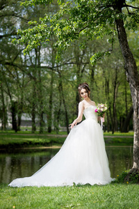 穿白色连衣裙的新娘带花束。 婚礼，户外