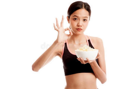 美丽的亚洲健康女孩吃薯片显示OK标志